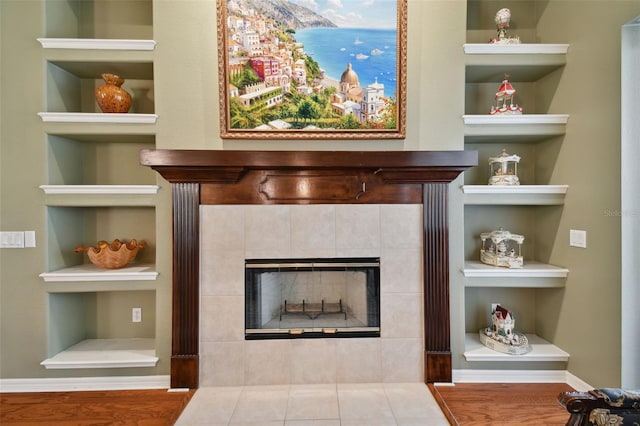 details with built in features, a water view, a tiled fireplace, and tile patterned flooring