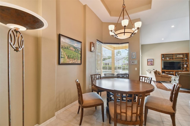 tiled dining area featuring a tray ceiling and a chandelier