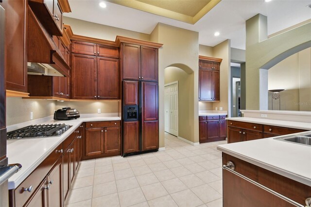 kitchen featuring stainless steel gas stovetop, sink, premium range hood, paneled fridge, and light tile patterned flooring