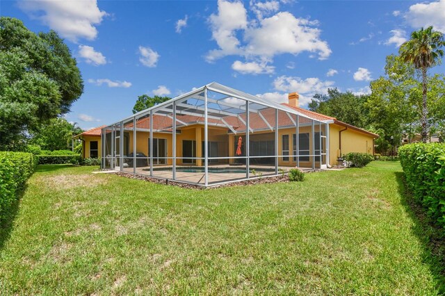 rear view of property featuring a lawn and a lanai