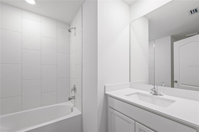 bathroom featuring tiled shower / bath, vanity, and a textured ceiling