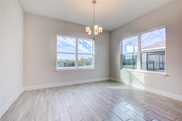 spare room with a notable chandelier and light hardwood / wood-style floors