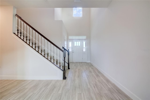 foyer featuring a towering ceiling and light hardwood / wood-style floors