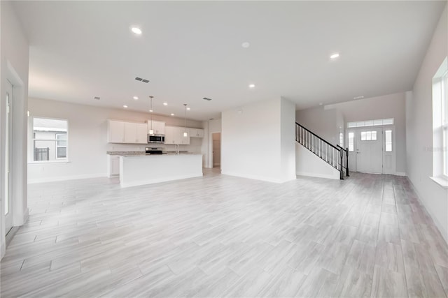 unfurnished living room featuring a healthy amount of sunlight and light wood-type flooring