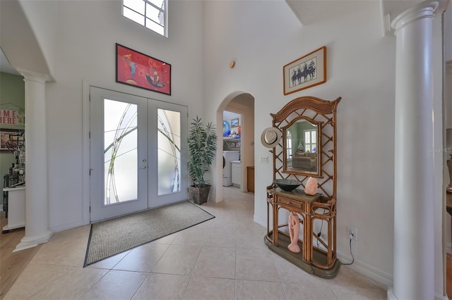 tiled entrance foyer with ornate columns, a towering ceiling, and french doors