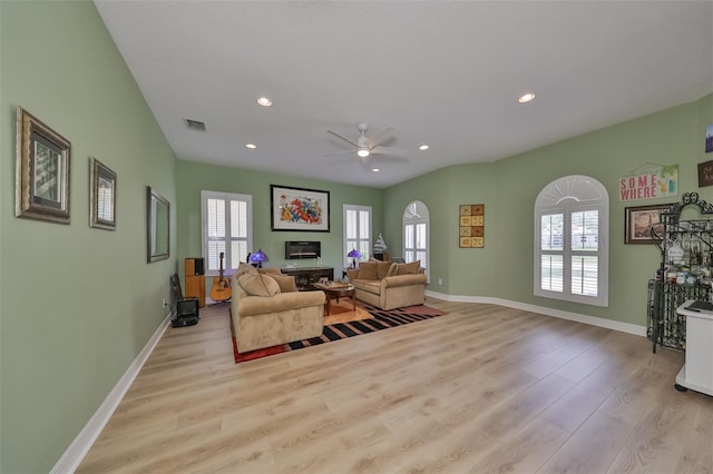 living room with ceiling fan, light wood-type flooring, and a fireplace