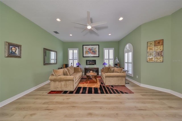 living room featuring a fireplace, ceiling fan, and light wood-type flooring