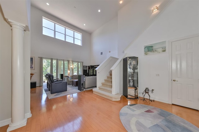 living room featuring light wood-type flooring, decorative columns, and a high ceiling