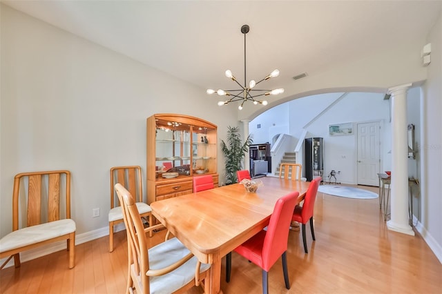 dining room with an inviting chandelier, light hardwood / wood-style floors, and ornate columns