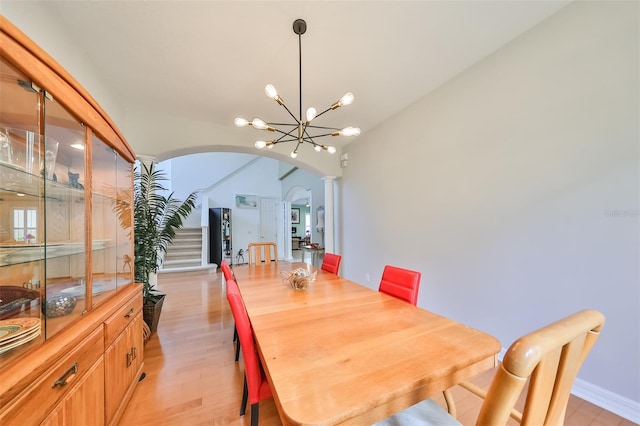 dining area featuring an inviting chandelier, light hardwood / wood-style floors, and decorative columns