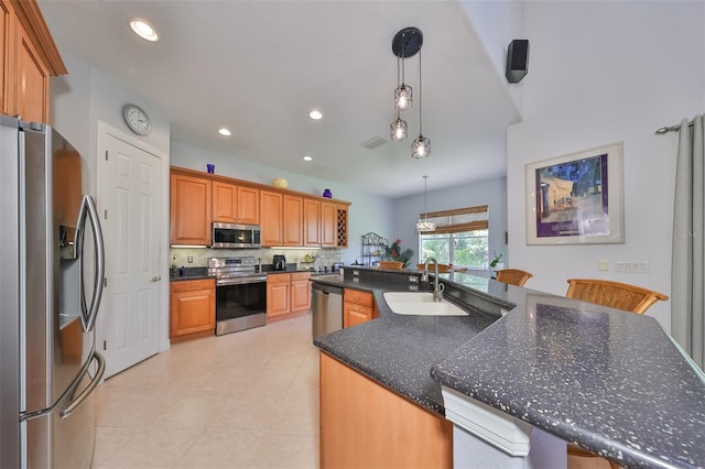 kitchen featuring sink, a breakfast bar area, hanging light fixtures, stainless steel appliances, and a center island with sink