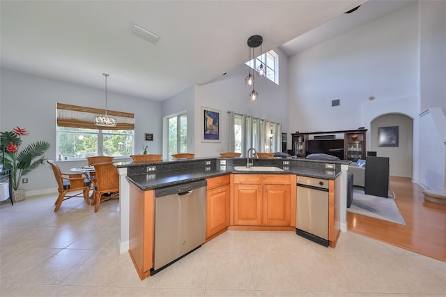 kitchen with sink, decorative light fixtures, dishwasher, and a center island with sink