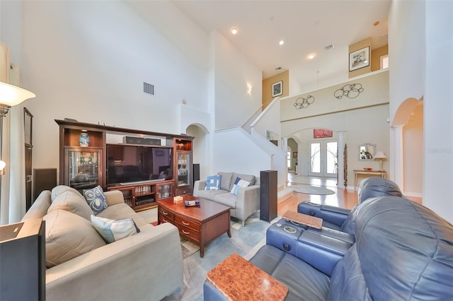 living room featuring french doors, light wood-type flooring, and a high ceiling