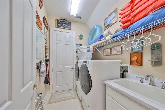 washroom featuring sink, a textured ceiling, and washer and clothes dryer