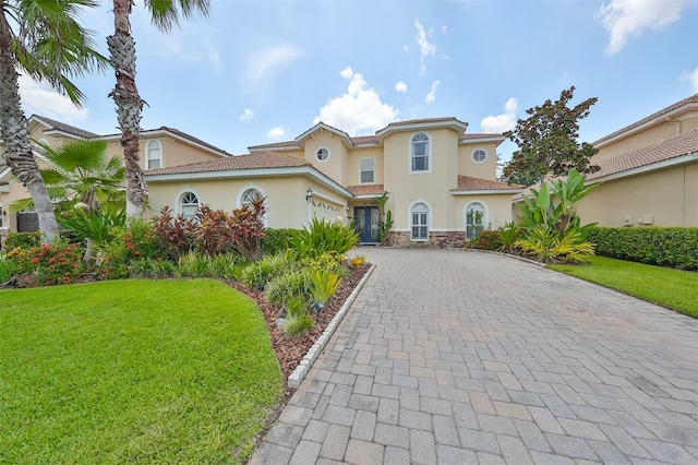 mediterranean / spanish home with a garage and a front lawn