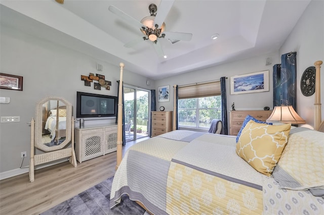 bedroom featuring ceiling fan, wood-type flooring, and a raised ceiling