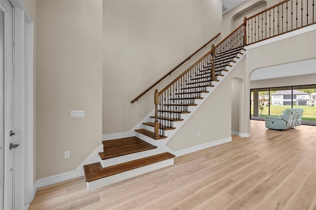 staircase with a high ceiling and hardwood / wood-style flooring