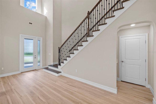 entryway featuring a towering ceiling and light hardwood / wood-style floors