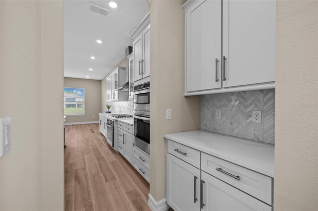 kitchen featuring light wood-type flooring, white cabinetry, and tasteful backsplash