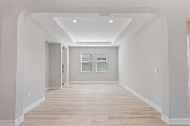 unfurnished room featuring a raised ceiling and light hardwood / wood-style flooring