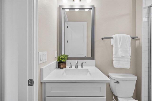 bathroom with walk in shower, vanity, and toilet