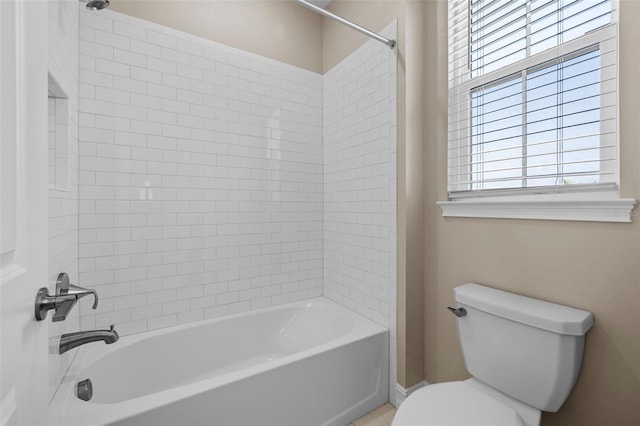 bathroom featuring tiled shower / bath combo and toilet