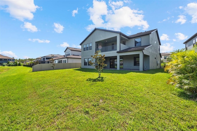 rear view of house with a balcony and a lawn