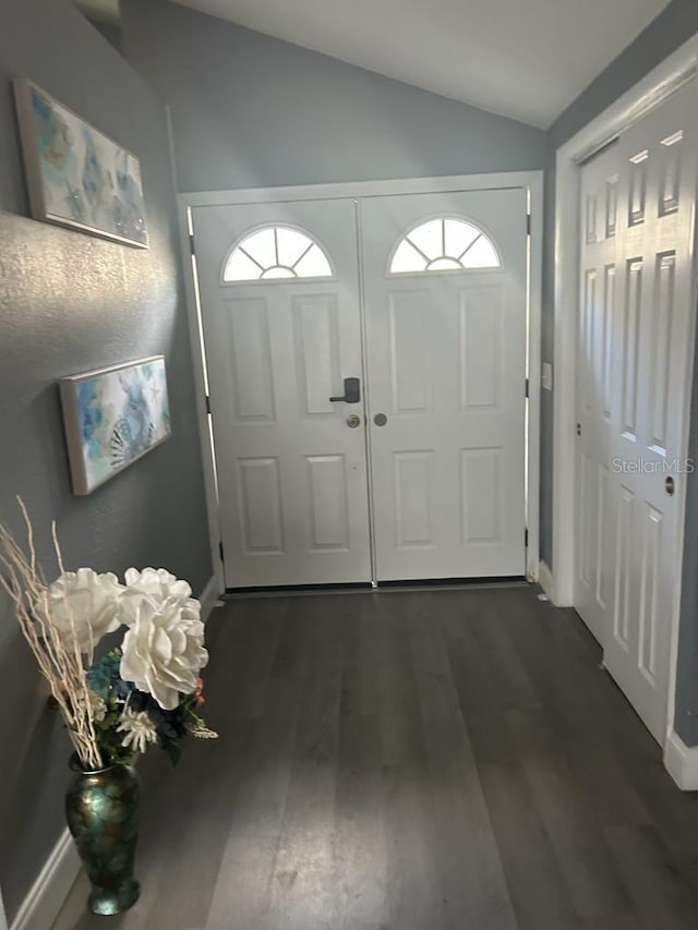 doorway featuring lofted ceiling, dark wood-style floors, and baseboards