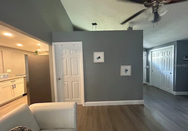 kitchen with light wood-style flooring, baseboards, a textured ceiling, and freestanding refrigerator