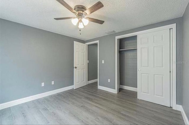 unfurnished bedroom with ceiling fan, a textured ceiling, hardwood / wood-style flooring, and a closet