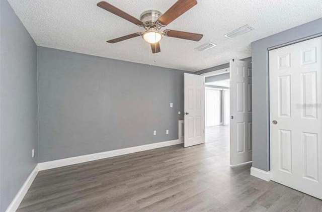 unfurnished bedroom with a closet, a textured ceiling, ceiling fan, and hardwood / wood-style floors