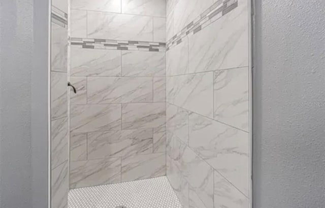 full bath with a textured wall and tiled shower