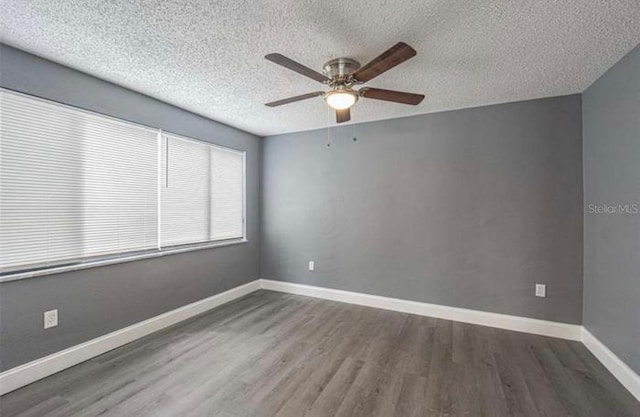 spare room featuring a ceiling fan, a textured ceiling, baseboards, and wood finished floors