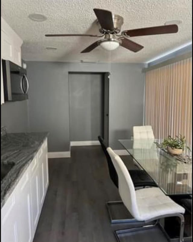 dining area featuring dark hardwood / wood-style floors, a textured ceiling, and ceiling fan