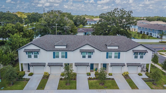 view of property with roof with shingles, driveway, and an attached garage