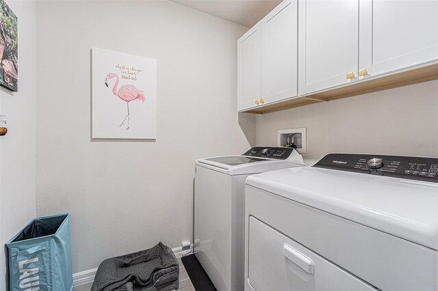 washroom featuring separate washer and dryer, cabinets, and light wood-type flooring