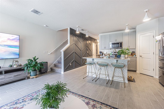 kitchen featuring gray cabinets, appliances with stainless steel finishes, a textured ceiling, and a breakfast bar