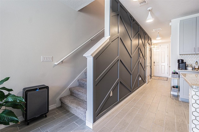 stairs featuring light hardwood / wood-style flooring and a textured ceiling