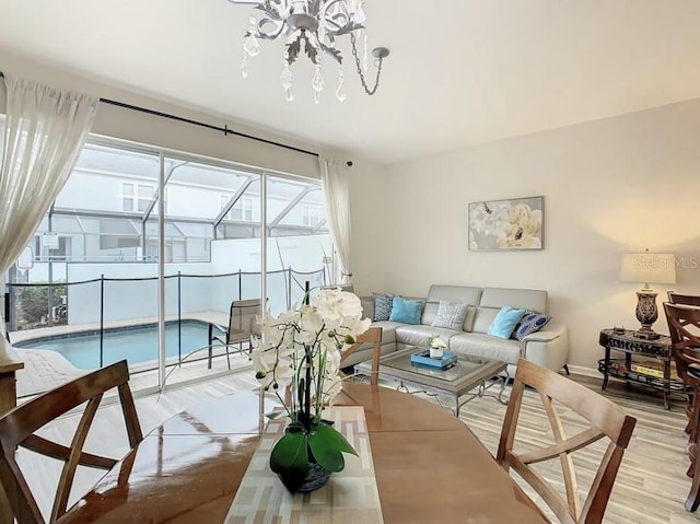 living room with a healthy amount of sunlight, light hardwood / wood-style floors, and a chandelier