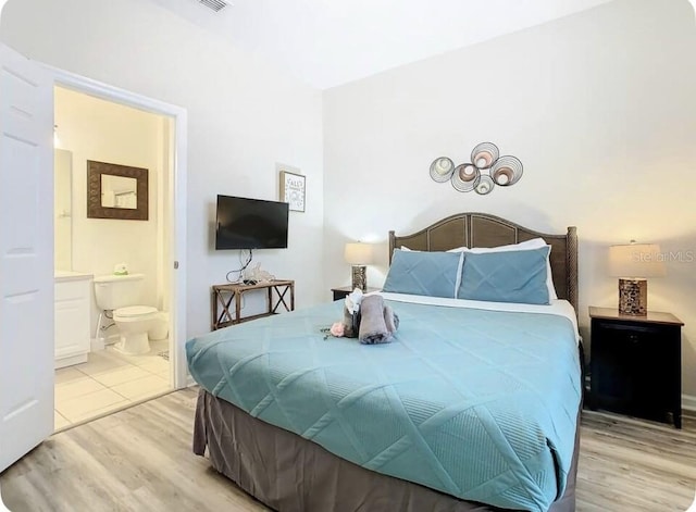 bedroom with light hardwood / wood-style flooring and ensuite bath