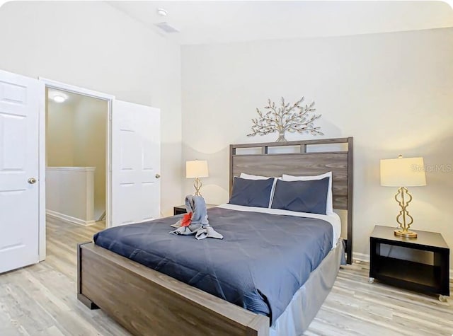 bedroom featuring a towering ceiling and light wood-type flooring