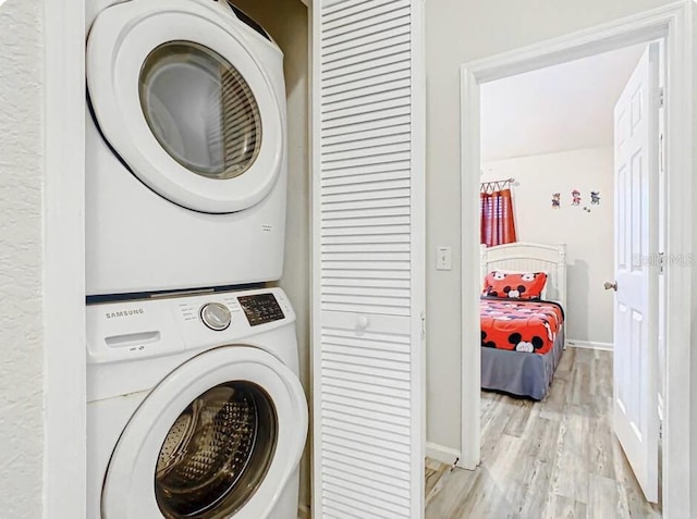 clothes washing area featuring light hardwood / wood-style floors and stacked washer and clothes dryer