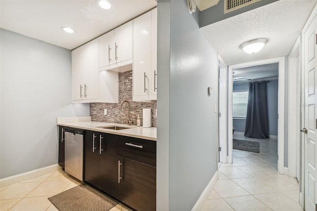 kitchen featuring dark brown cabinetry, sink, light tile patterned floors, dishwasher, and white cabinets