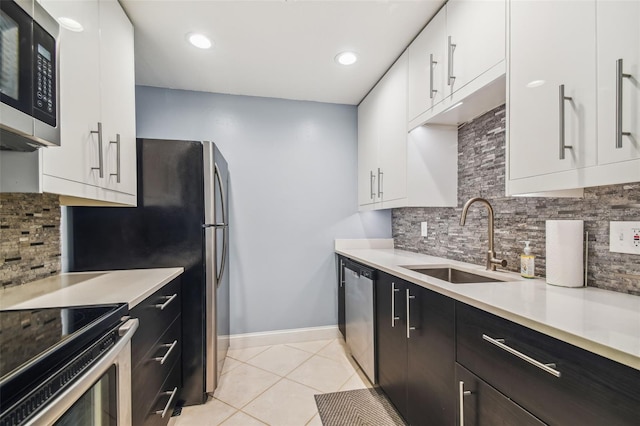 kitchen featuring sink, light tile patterned floors, appliances with stainless steel finishes, decorative backsplash, and white cabinets