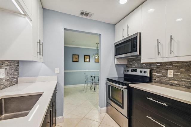 kitchen featuring sink, white cabinetry, light tile patterned floors, appliances with stainless steel finishes, and backsplash