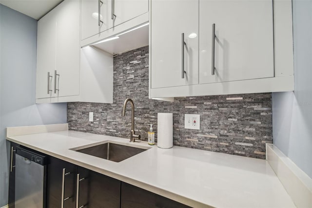 kitchen featuring tasteful backsplash, stainless steel dishwasher, white cabinetry, and sink