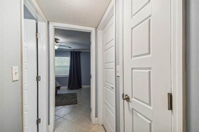 hallway featuring light tile patterned floors and a textured ceiling