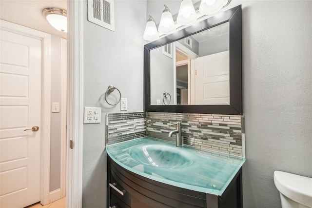 bathroom with vanity, toilet, and decorative backsplash