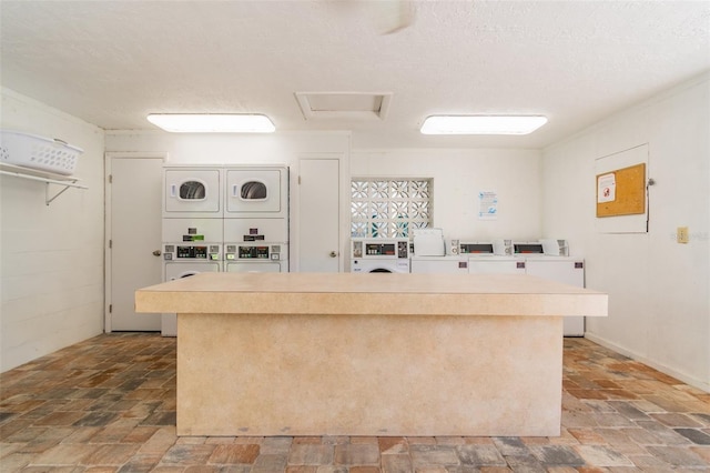 kitchen with stacked washer / drying machine and a textured ceiling