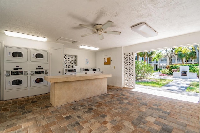 kitchen with ceiling fan, stacked washing maching and dryer, independent washer and dryer, a center island, and a textured ceiling